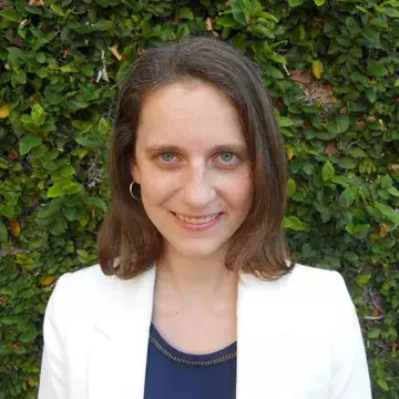 Headshot of a woman wear a navy shirt and white blazer